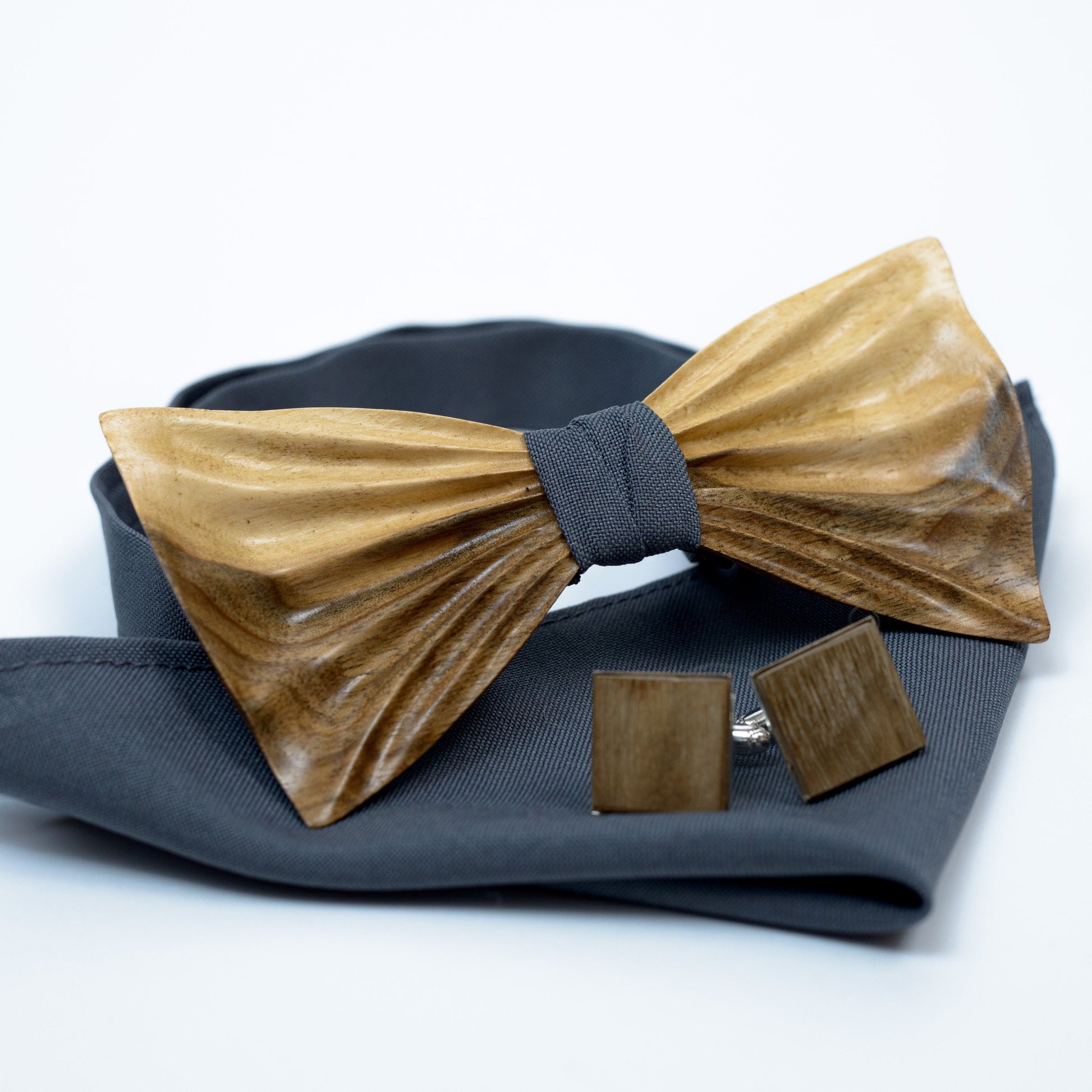 Close-up of a walnut wood bowtie with a smooth 3D curved design, imitating a classic fabric bow tie.