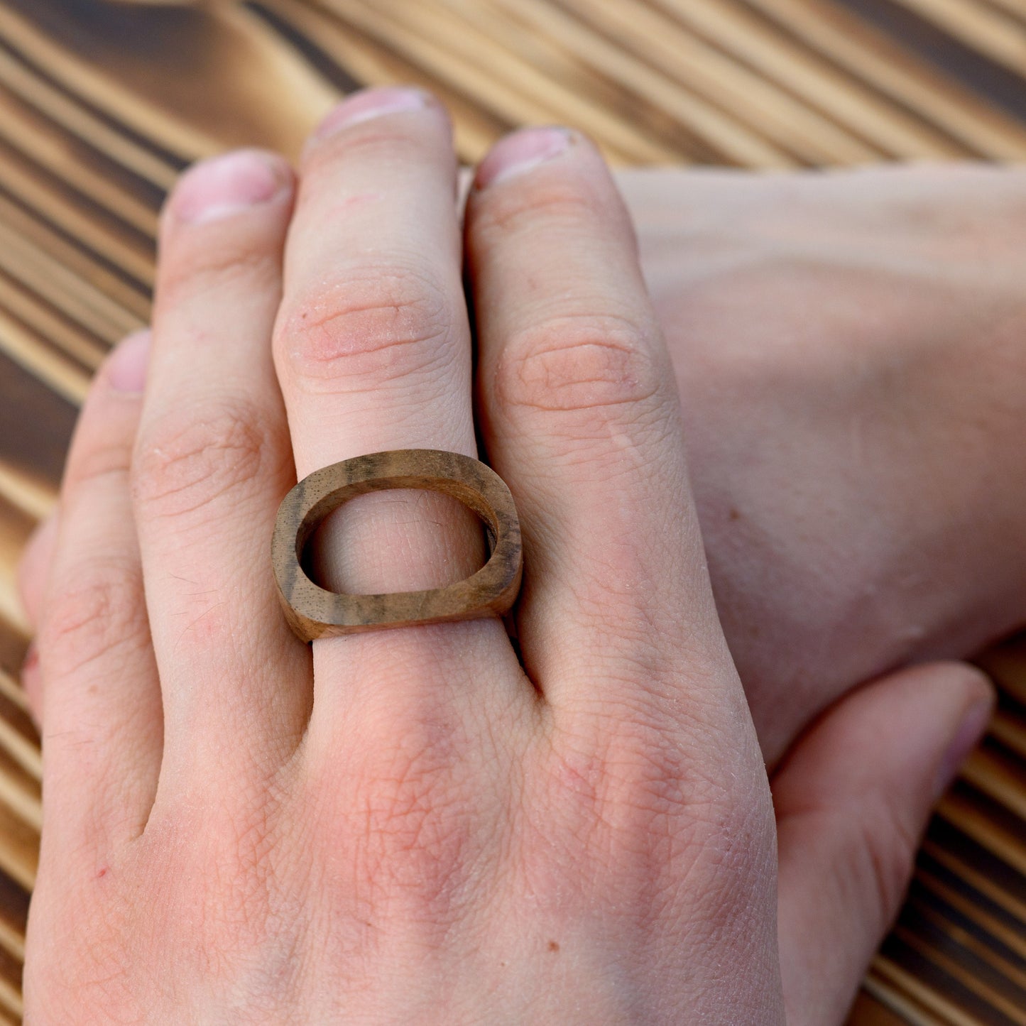 Walnut wood ring on a man's hand, showing its elegant and comfortable fit