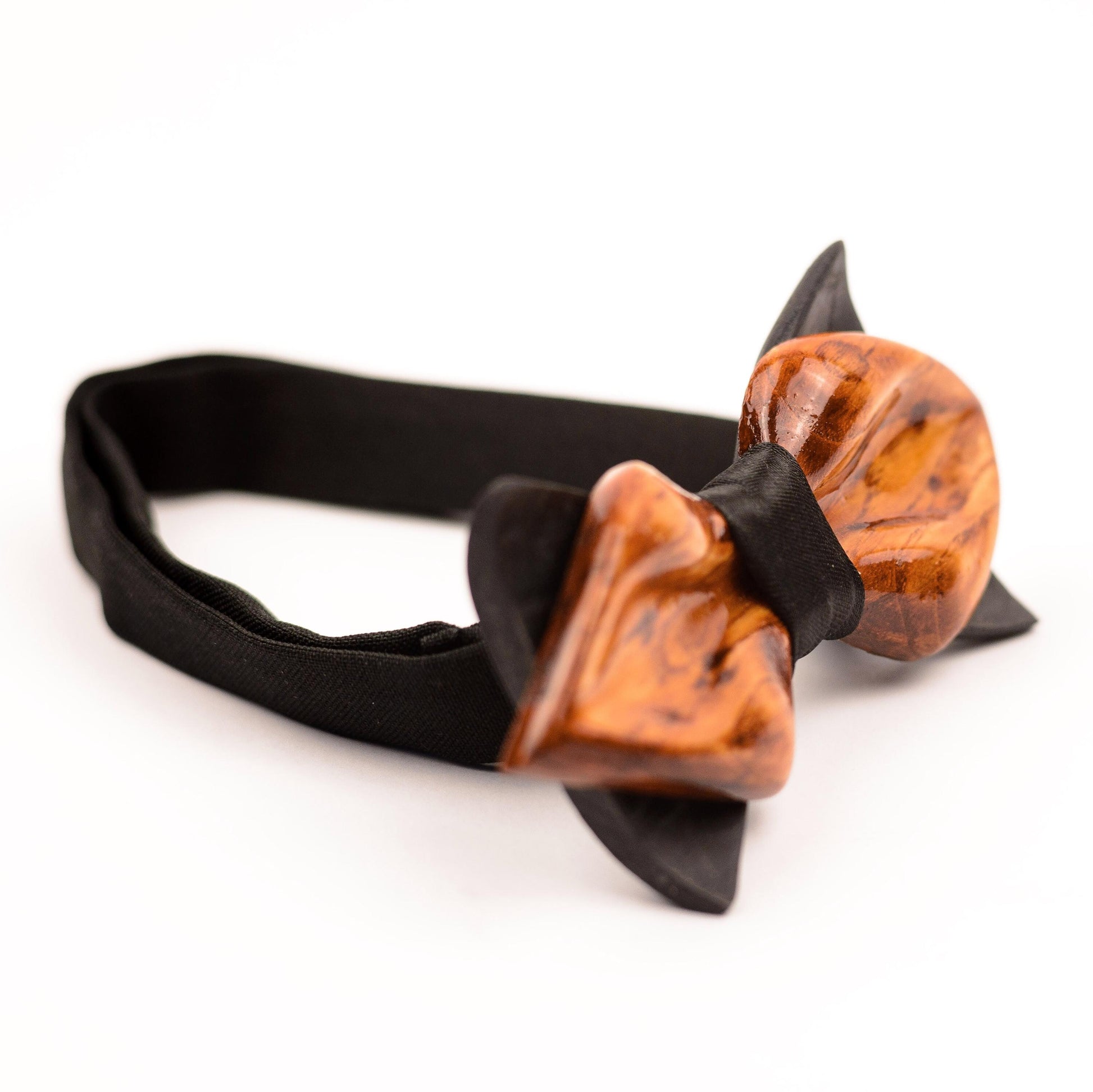 A wooden bow tie with a brown and orange wood grain pattern. The bow tie is attached to a black adjustable strap.