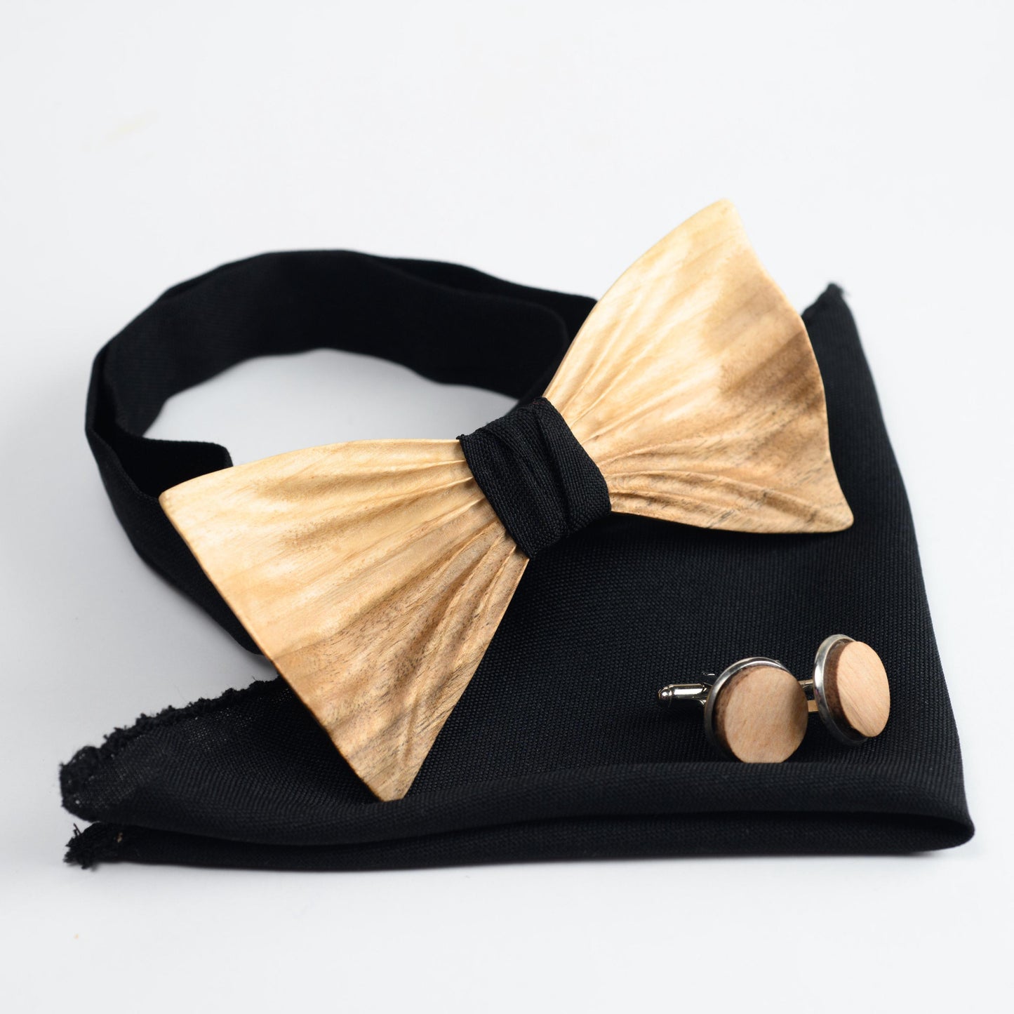 Wedding accessories set featuring a wooden bow tie, matching pocket square, and monogram cufflinks.