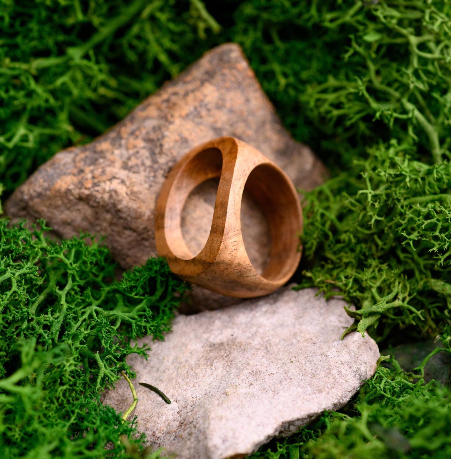 Close-up of a natural wooden ring, showcasing the rich walnut grain and polished design.