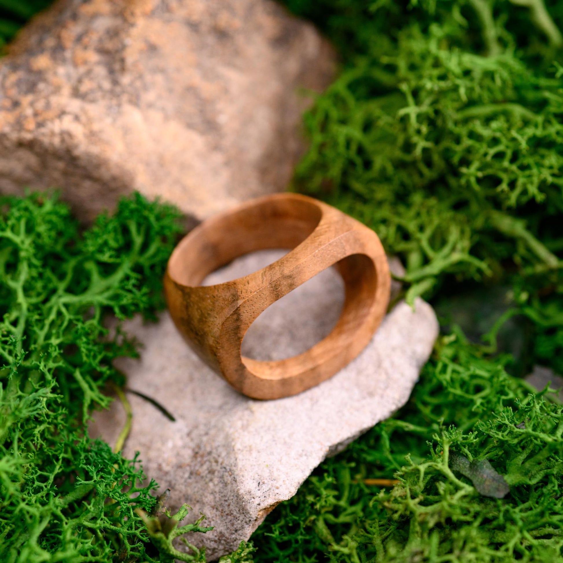 Custom wooden ring resting on a rustic background, highlighting its natural craftsmanship.