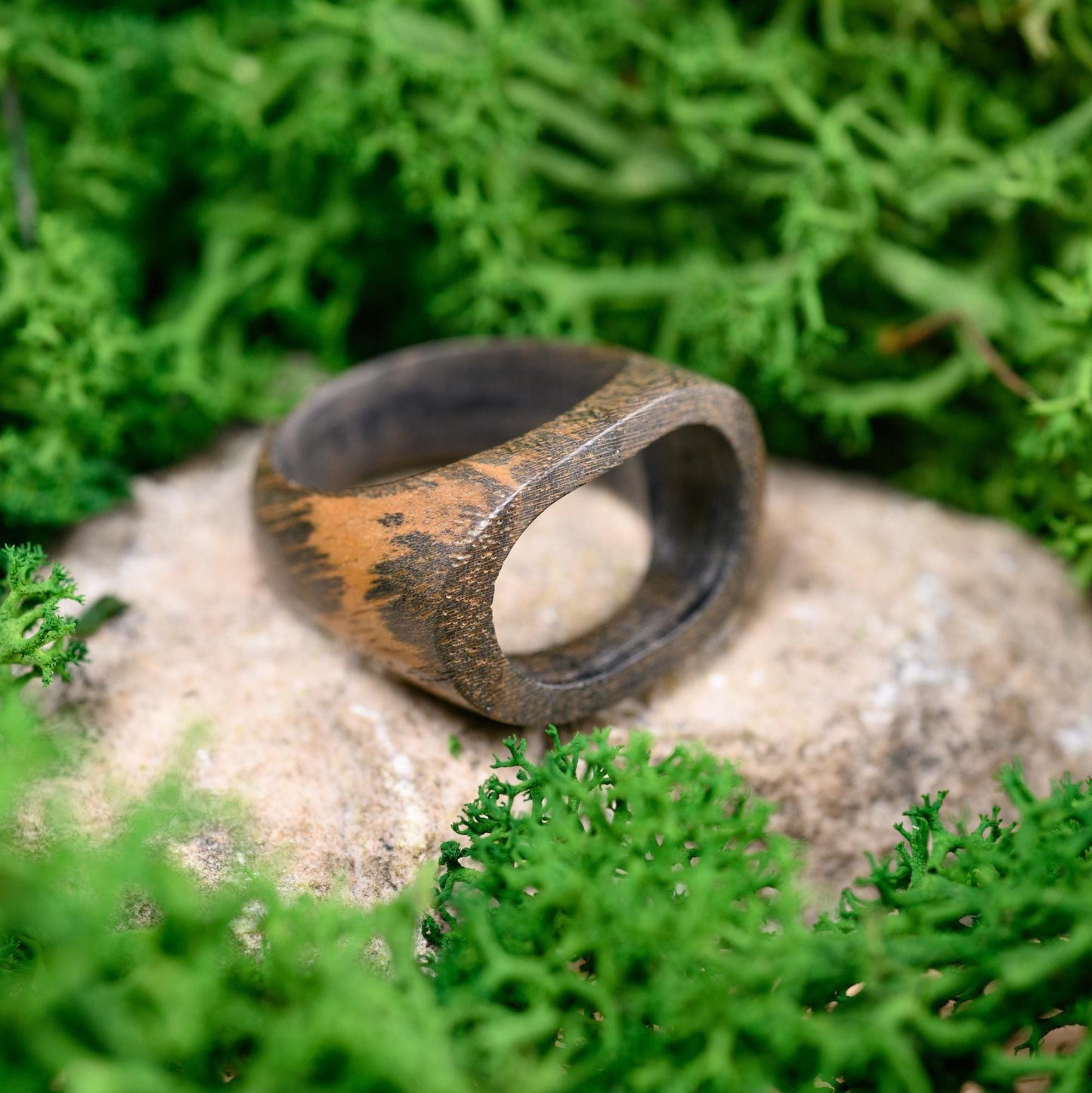 Custom wooden ring resting on a rustic background, highlighting its natural craftsmanship.