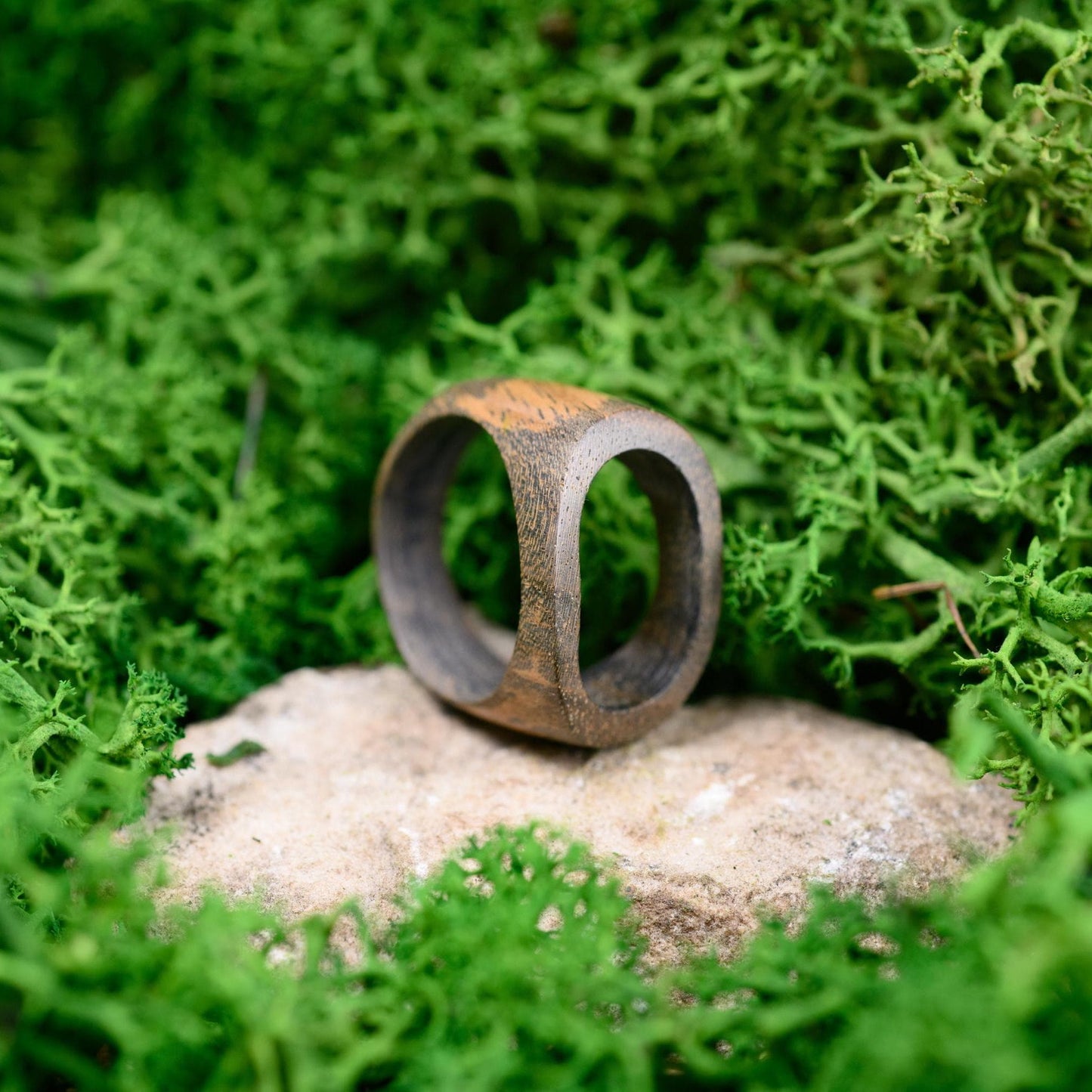 Close-up of a natural wooden ring, showcasing the rich walnut grain and polished design